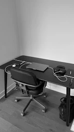 Minimalist black and white image of office desks with organized supplies and tech gadgets.