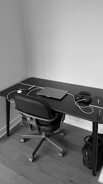 Monochrome photo of a sleek modern workspace with branding materials on a black desk.