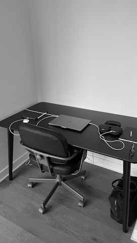 A sleek black and white photo of a minimalist office desk with a laptop and financial documents neatly arranged.