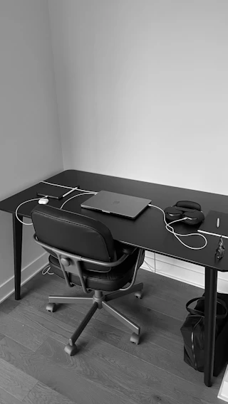 A minimalist black and white photo of a clean, modern workspace with subtle shadows.