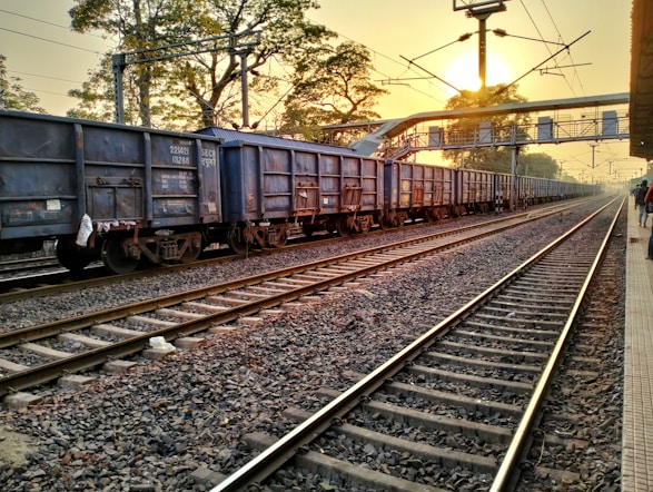 A seasoned consultant discussing rail logistics with a client beside a freight train yard at sunset.