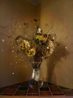 A cozy living room corner featuring a tall decorative vase filled with dried branches.