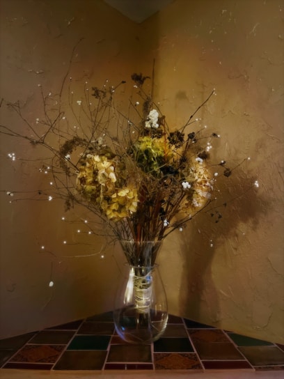 A cozy living room corner featuring a tall decorative vase filled with dried branches.