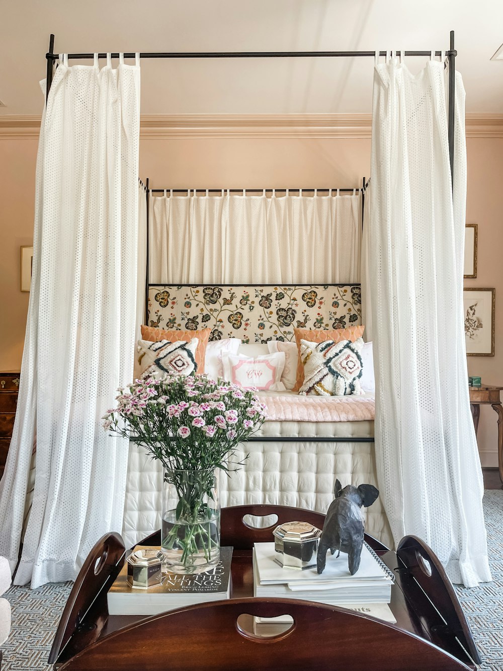 a bedroom with a canopy bed and a table with a vase of flowers on it