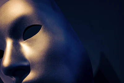 A close-up of a sleek black mask with gold accents resting on a dark velvet surface, illuminated by soft cinematic lighting.