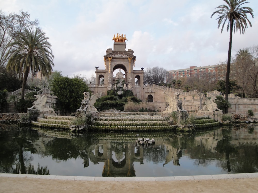 a pond with a fountain surrounded by palm trees