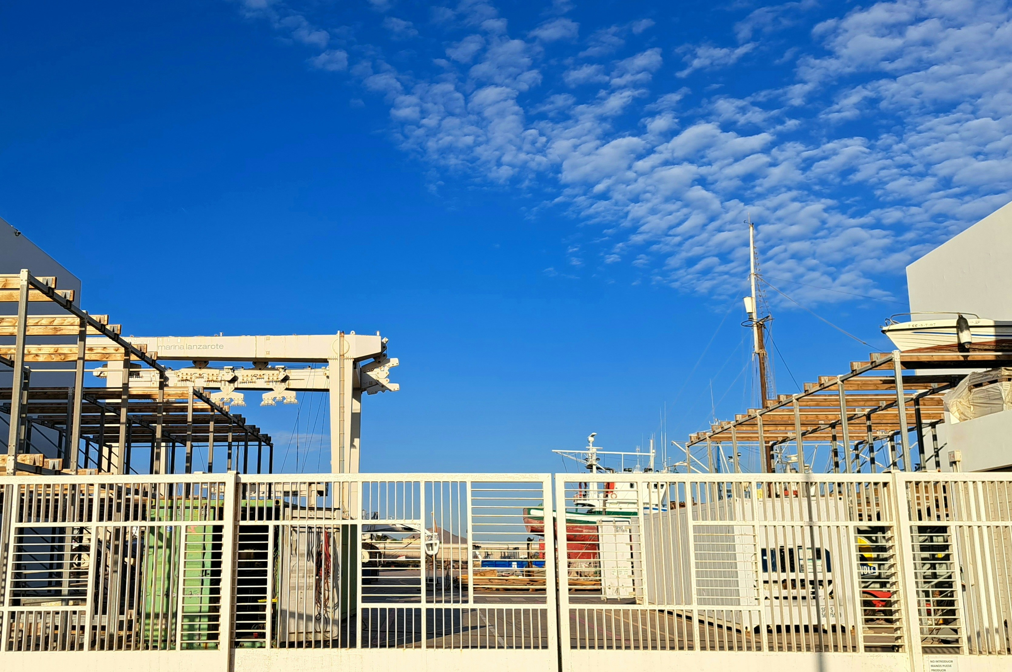 a white fence and some buildings under a blue sky