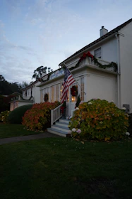 A professional real estate agent handing keys to happy new homeowners outside a charming colonial-style house.