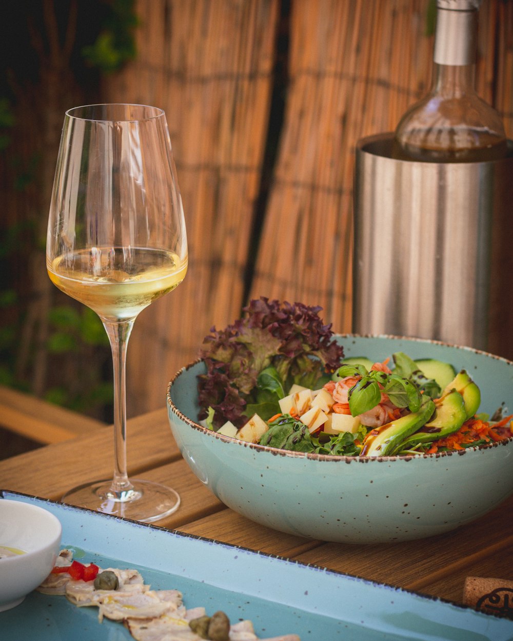 a bowl of food and a glass of wine on a table