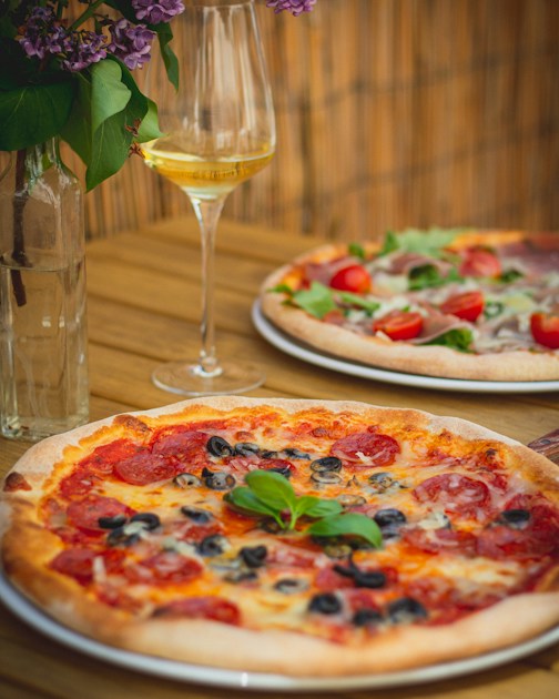Pizzas conviviales sur table en bois avec verre de vin
