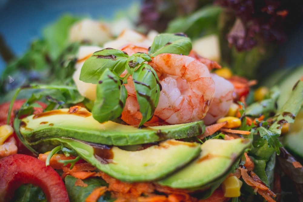 a salad with shrimp, avocado, carrots, and lettuce