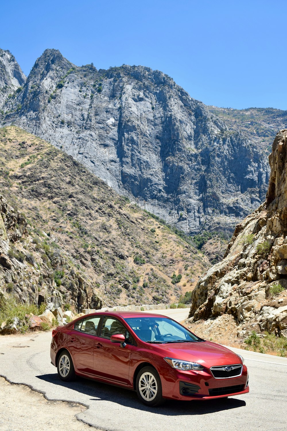 a red car driving down a mountain road