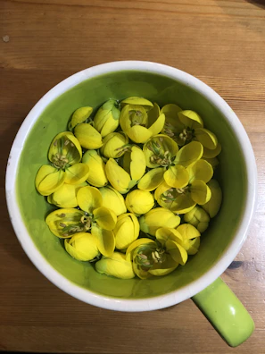 Stoneware cups in sunny yellow and soft green layered beside a fresh bouquet of wildflowers.