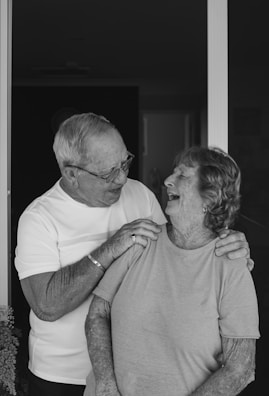 A black and white photo of an elderly couple sharing a gentle smile.