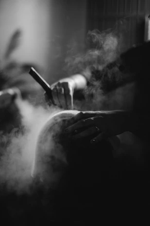 a black and white photo of a person smoking a cigarette