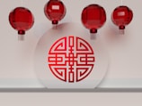 Red Chinese lanterns are suspended above a shelf with a circular white plaque displaying a traditional red Chinese symbol.