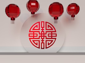 Red Chinese lanterns are suspended above a shelf with a circular white plaque displaying a traditional red Chinese symbol.