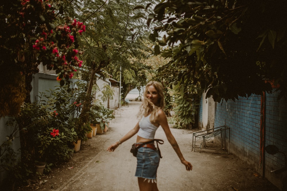 a woman is walking down a dirt road