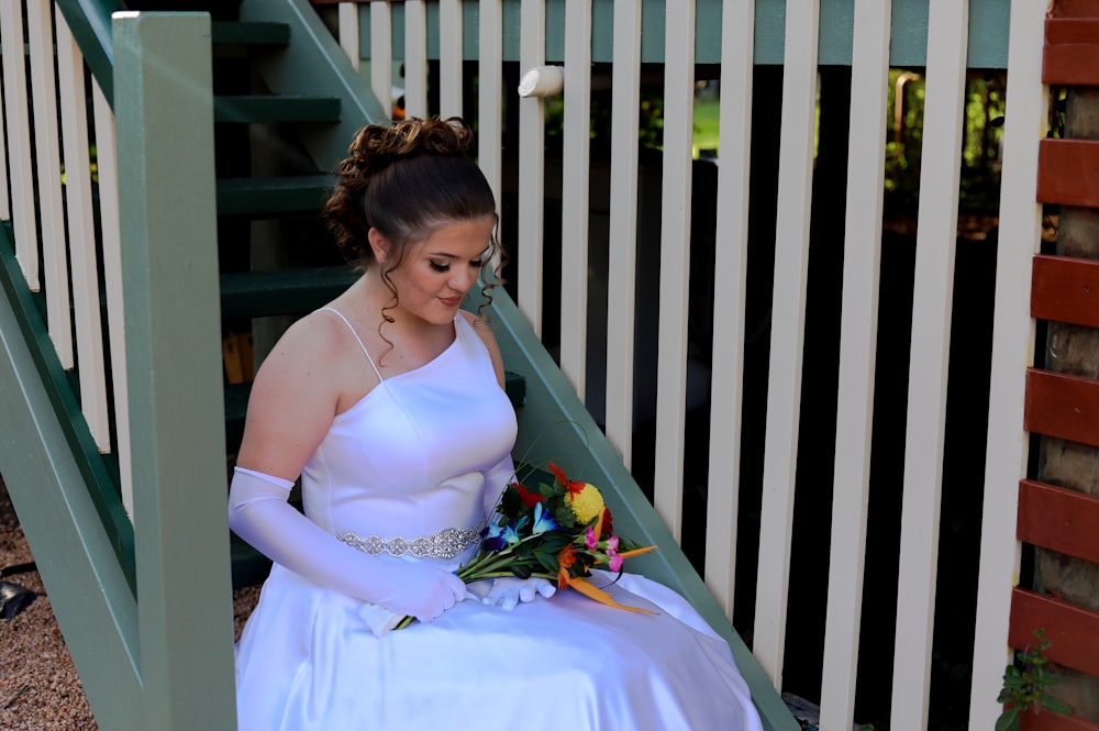 a woman in a white dress sitting on a stair case