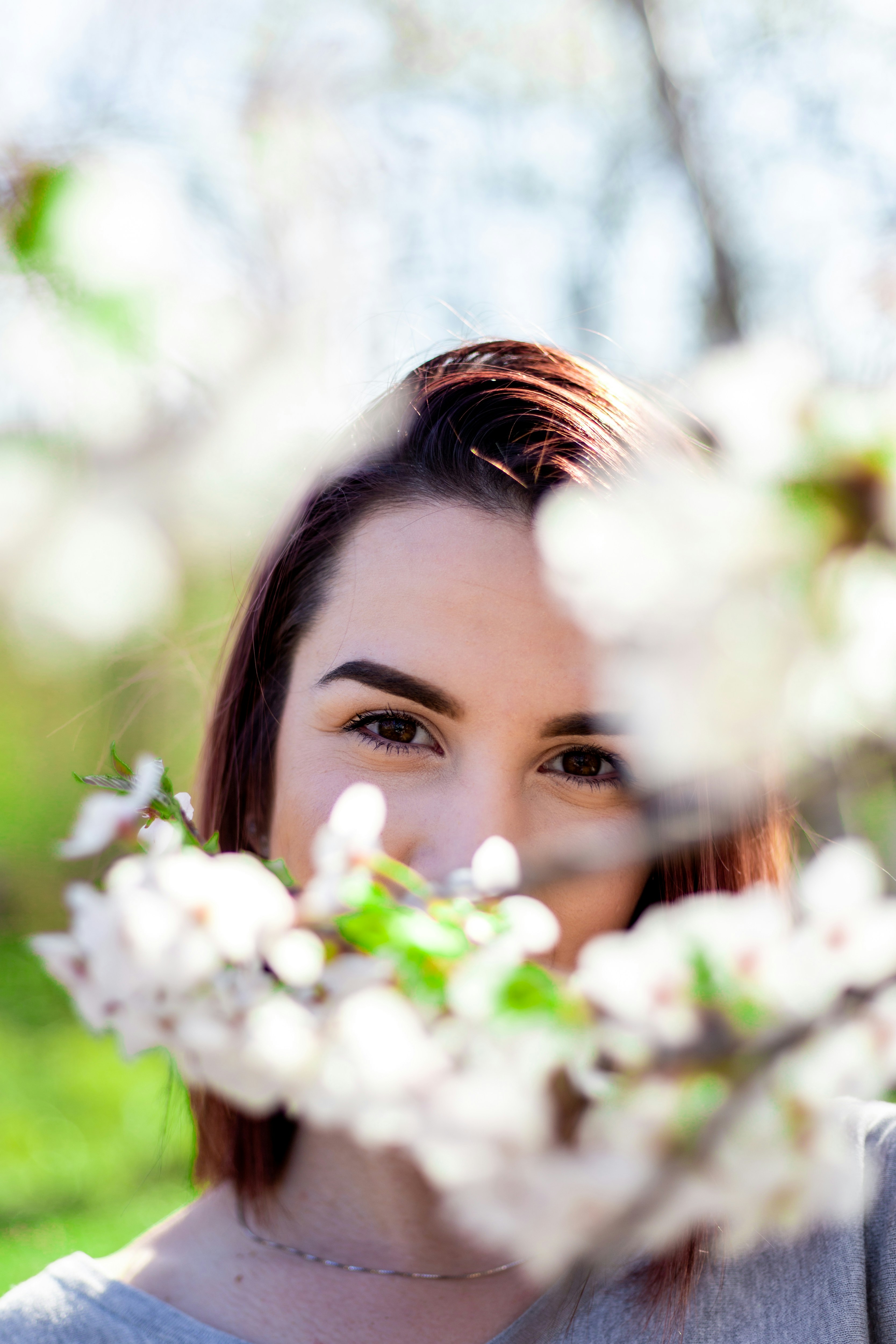 a woman standing in front of a tree with white flowers