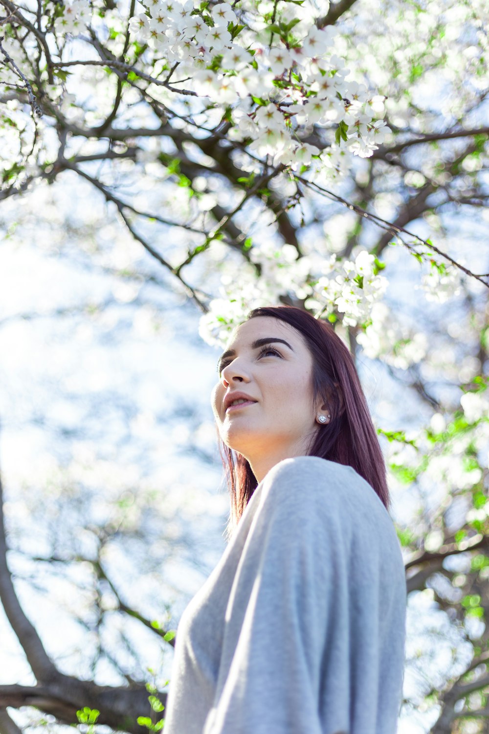 a woman standing in front of a tree with white flowers