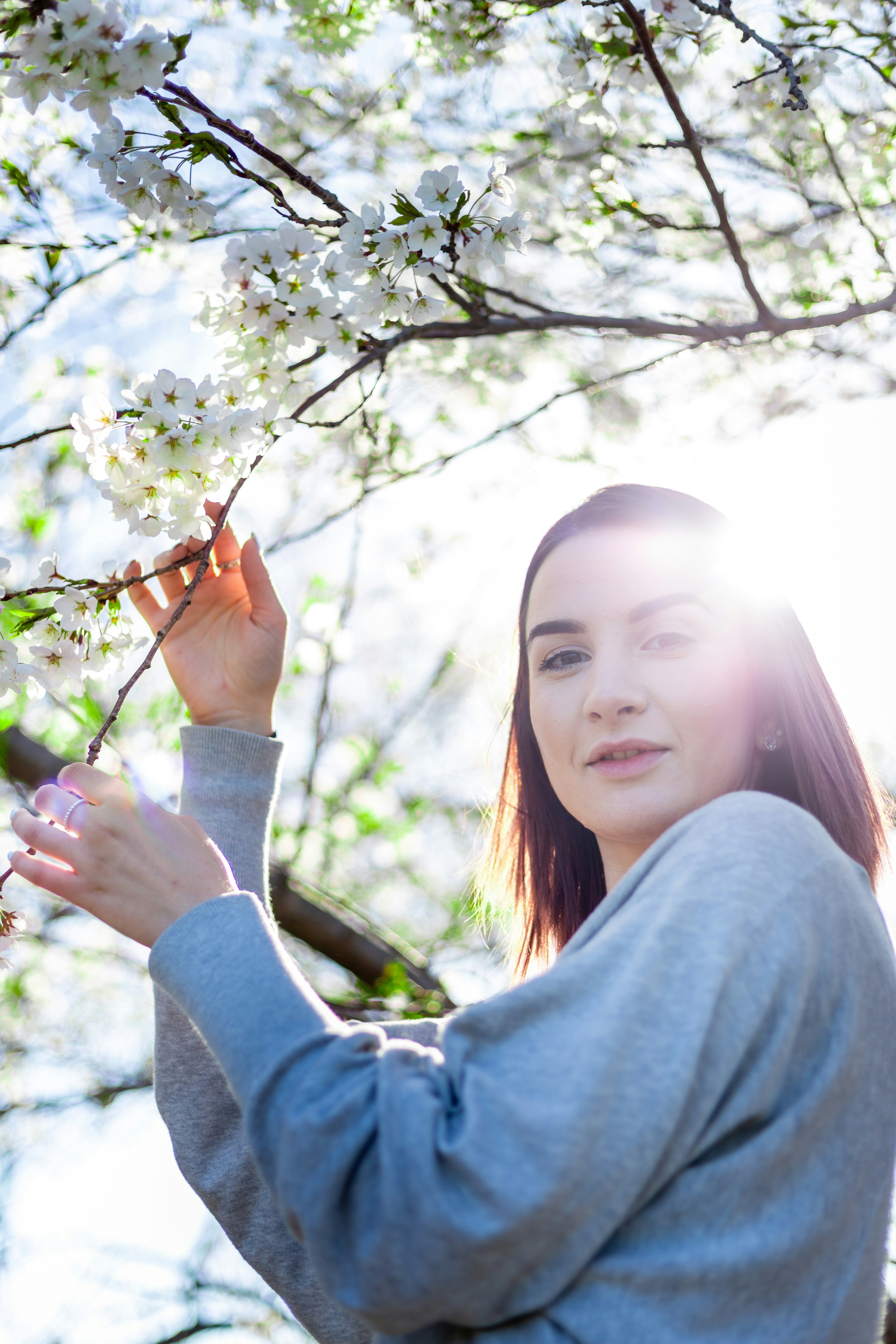a woman is holding a branch with white flowers