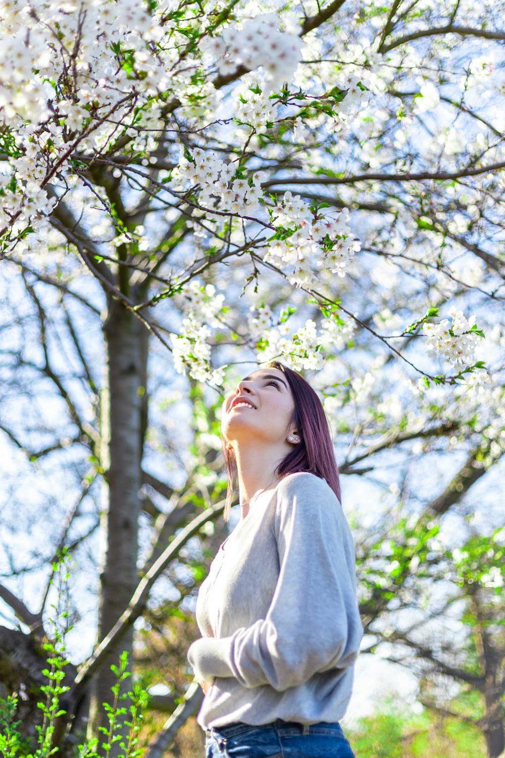 a woman standing in front of a tree with white flowers