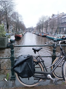 A set of waterproof pannier bags attached to an e-bike parked by a canal in Amsterdam.