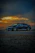 A sleek black luxury sedan parked on a scenic Montreal street at sunset.