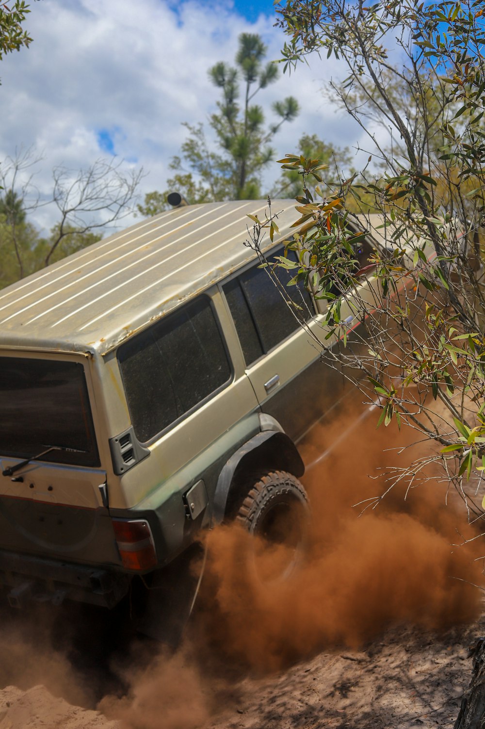 a truck driving down a dirt road next to a tree