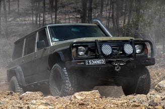 a black jeep driving through a forest filled with rocks