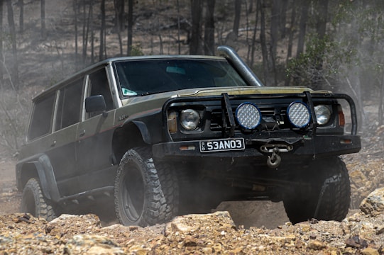 a black jeep driving through a forest filled with rocks