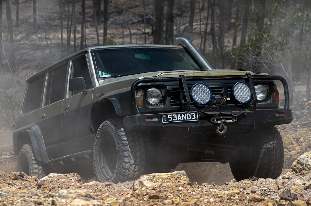 a black jeep driving through a forest filled with rocks