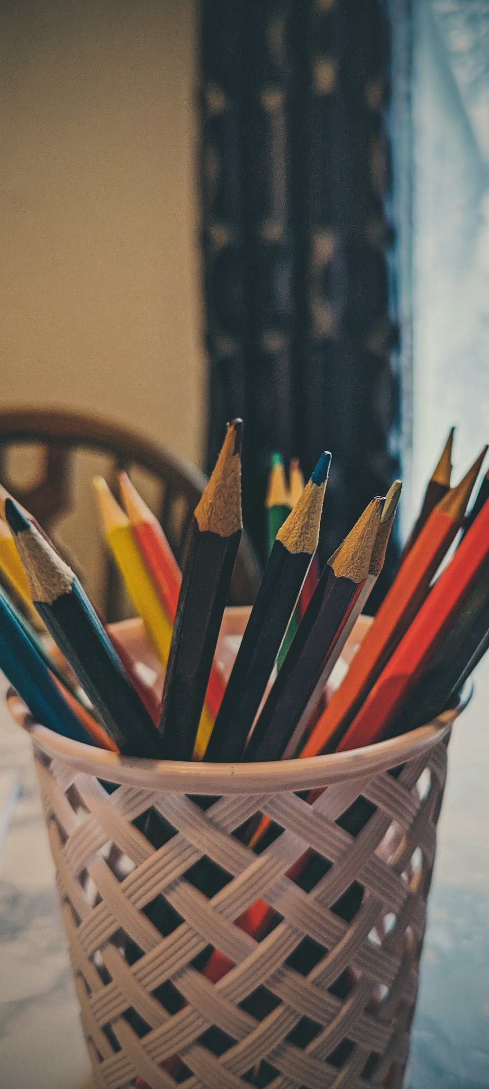 a basket full of colored pencils sitting on a table