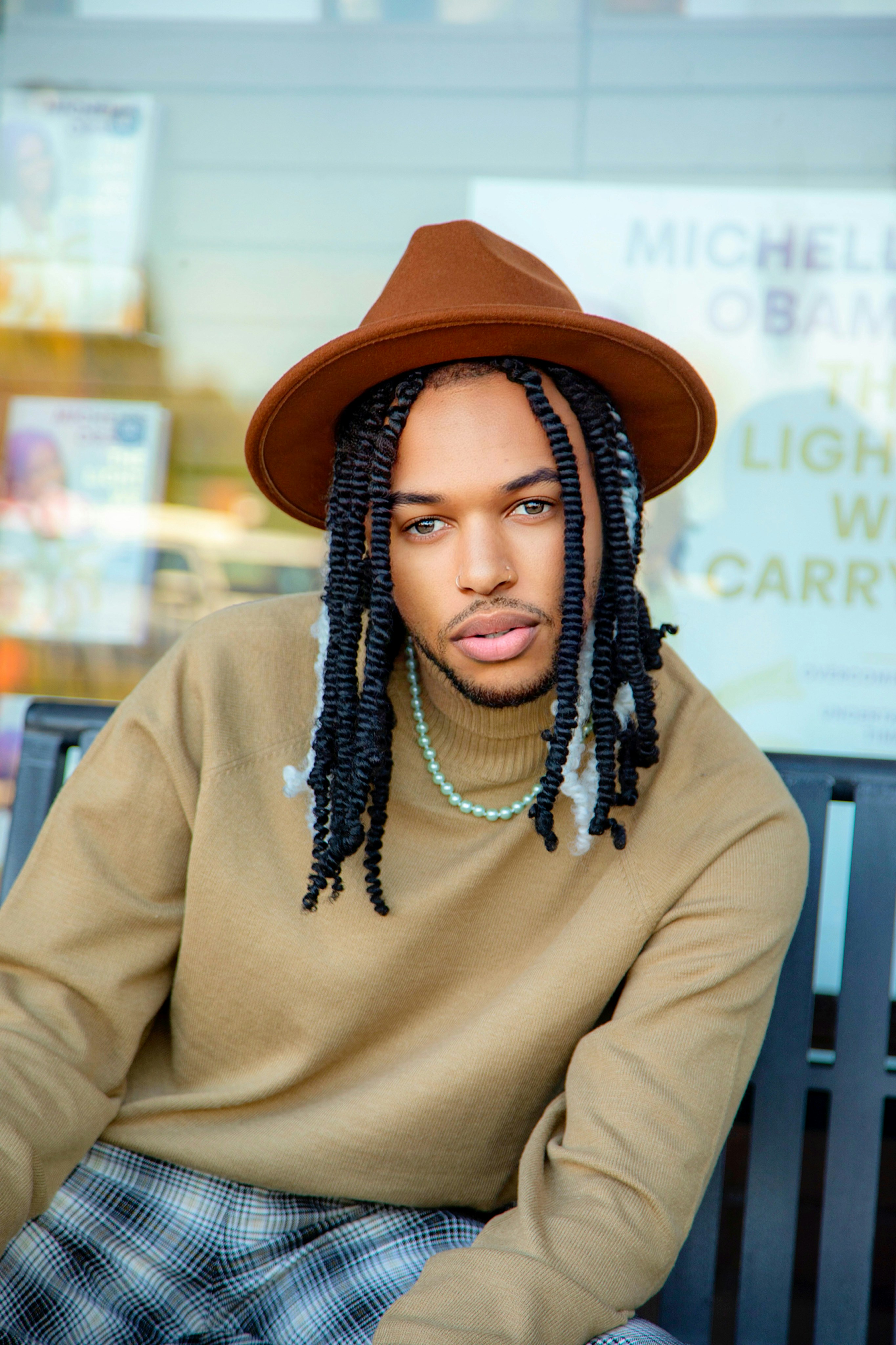 a man with dreadlocks sitting on a bench
