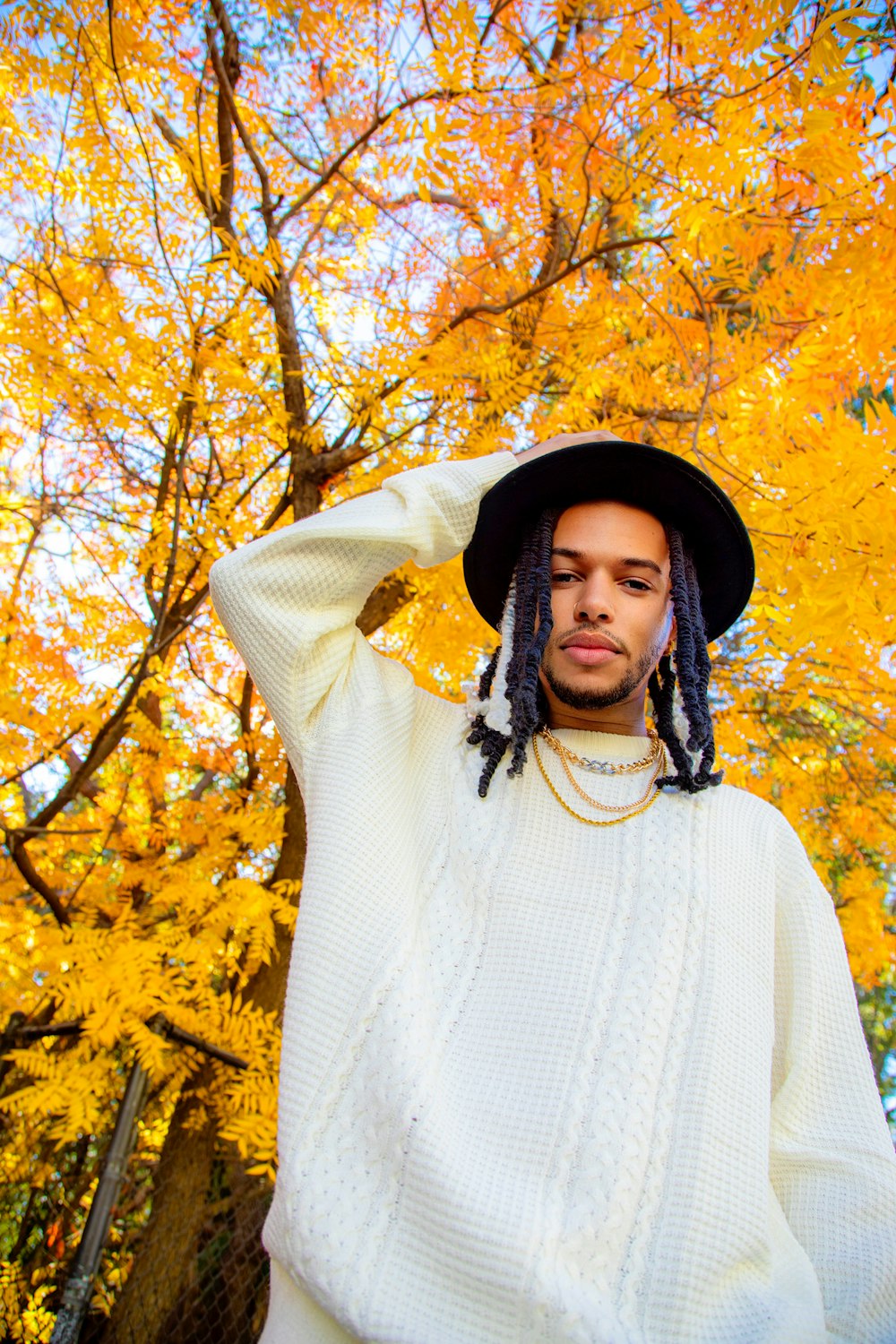 a man with dreadlocks standing in front of a tree