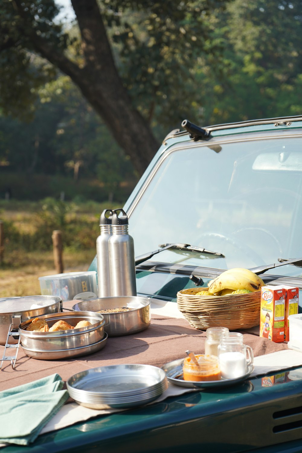 a picnic table with food on it and a car in the background