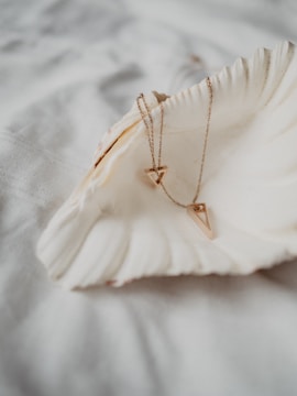 Close-up of a delicate necklace featuring a tiny seashell pendant from a coastal trip.