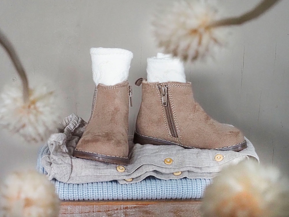 a pair of boots sitting on top of a pile of clothes