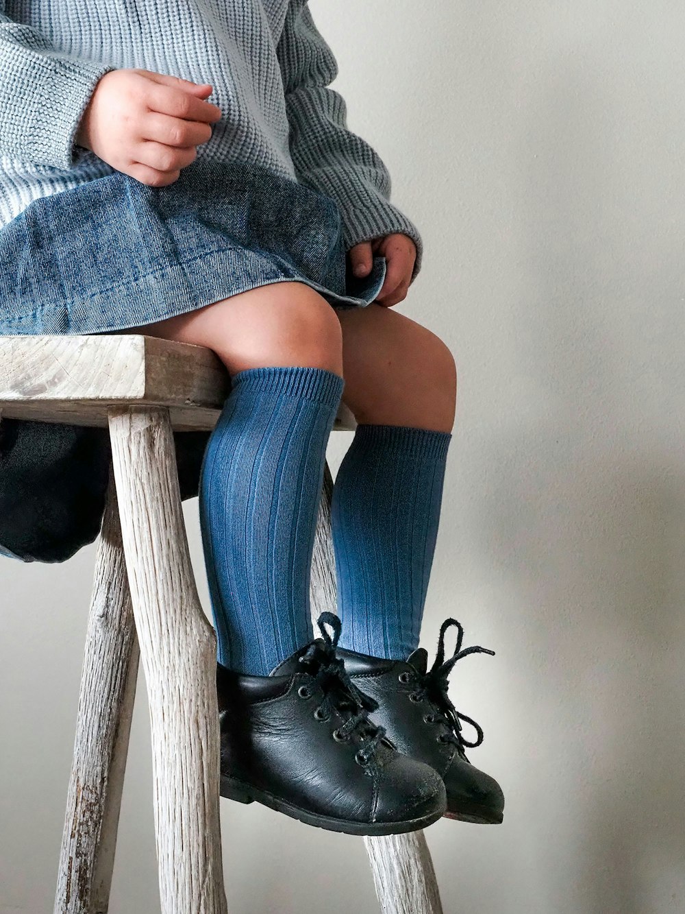 a little girl sitting on top of a wooden stool