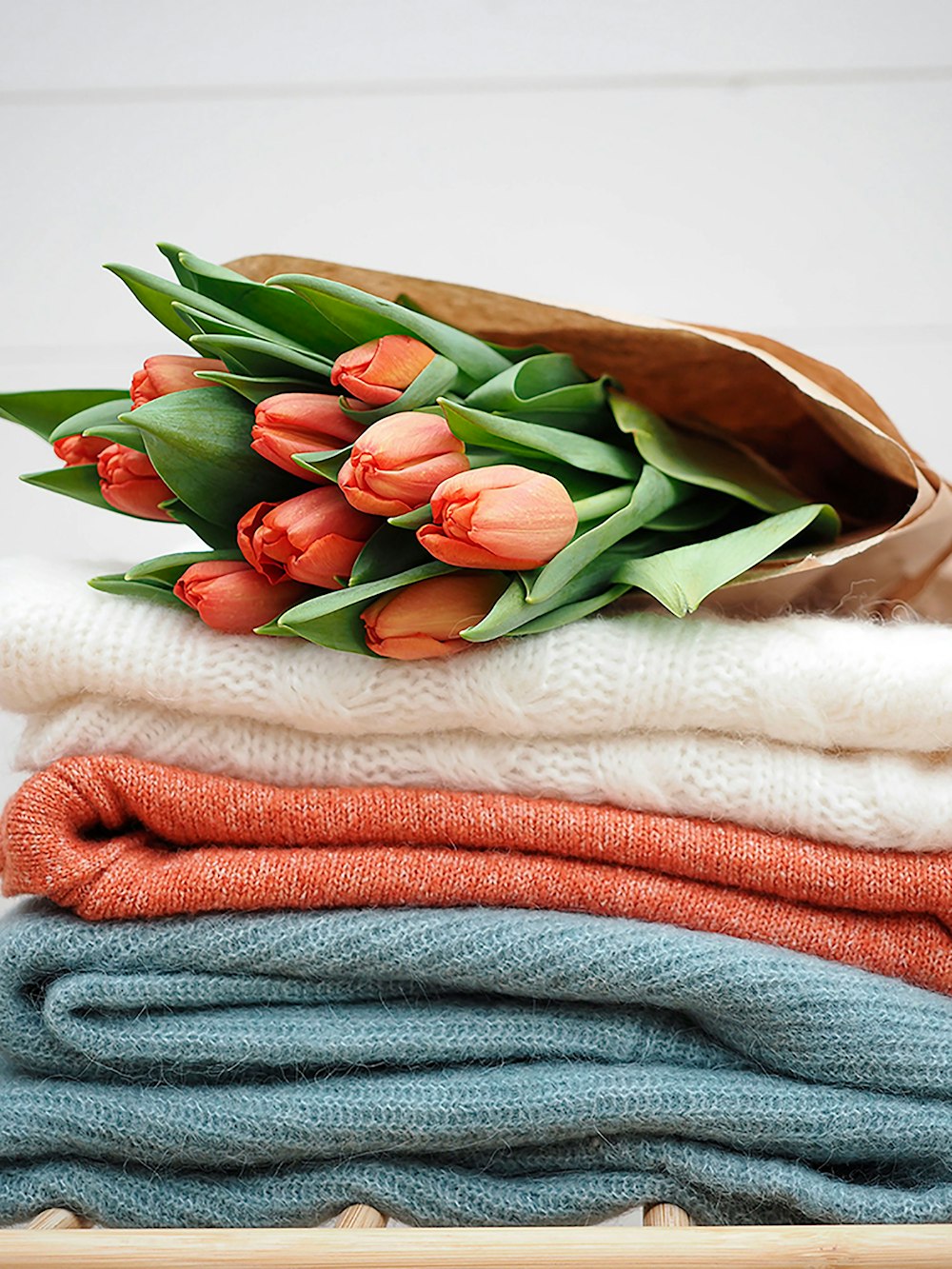 a bunch of tulips sitting on top of a pile of sweaters