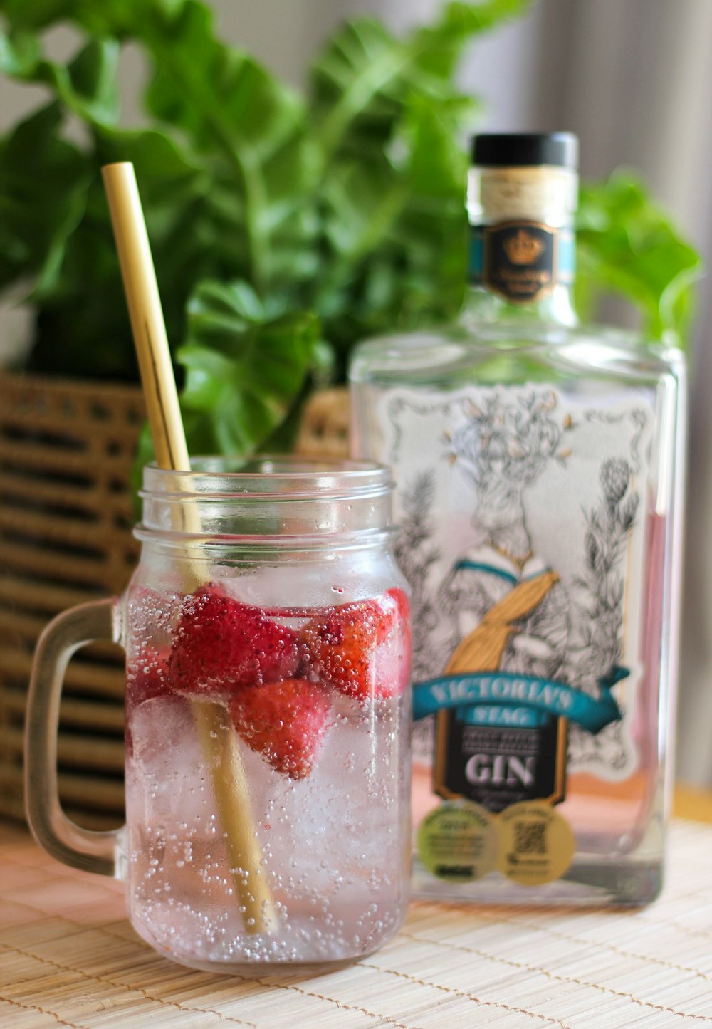 a bottle of gin and a strawberries in a jar