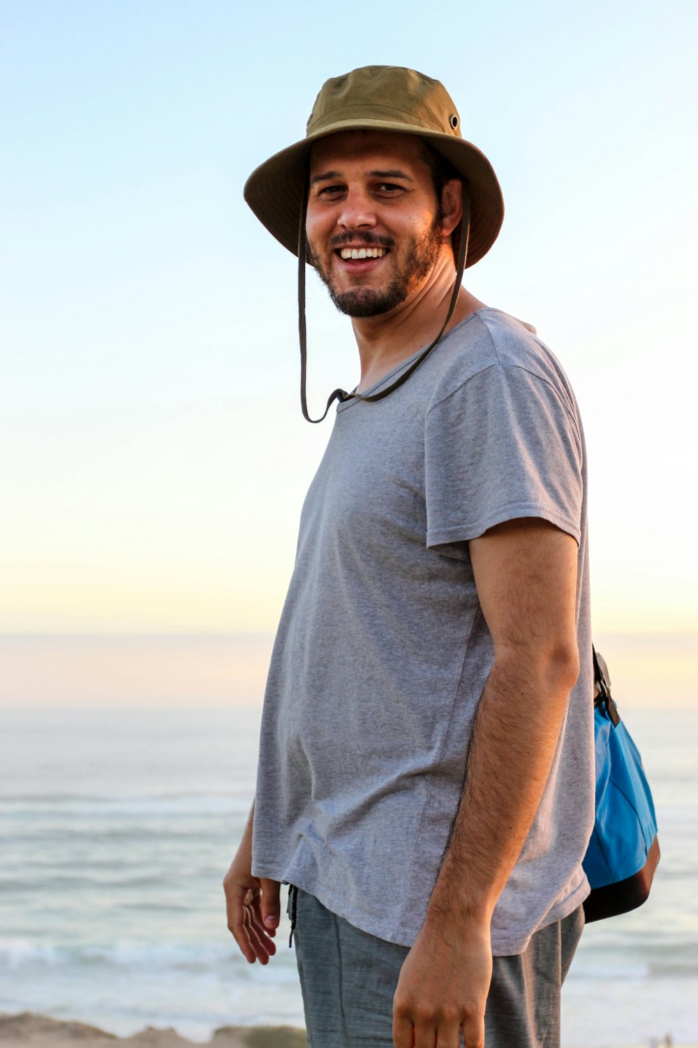 a man wearing a hat standing on a beach