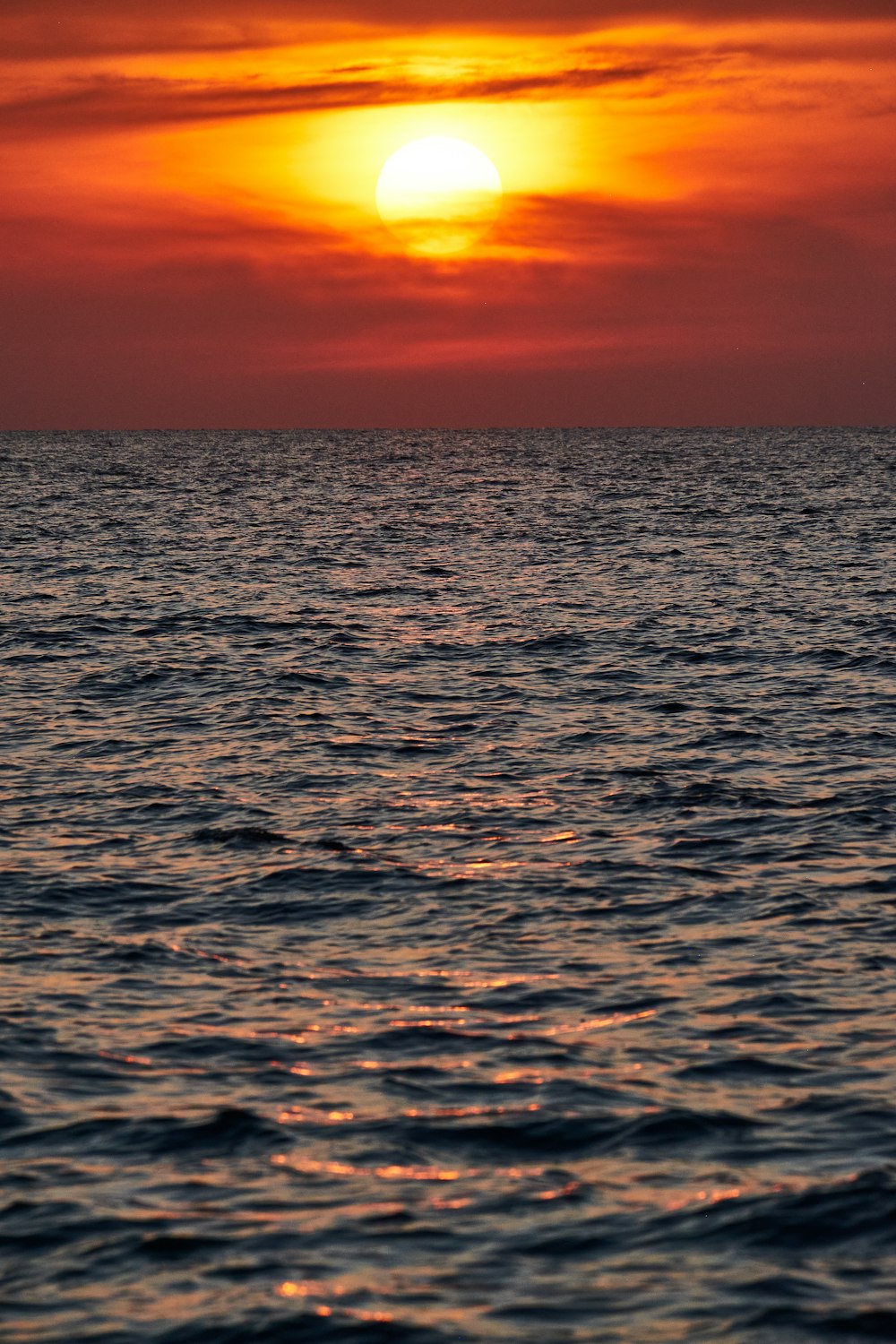 a sunset over the ocean with a boat in the water