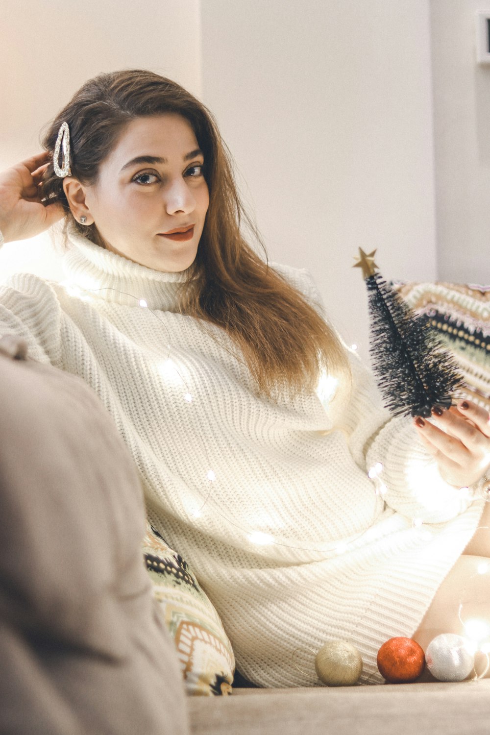 a woman sitting on a couch holding a christmas tree