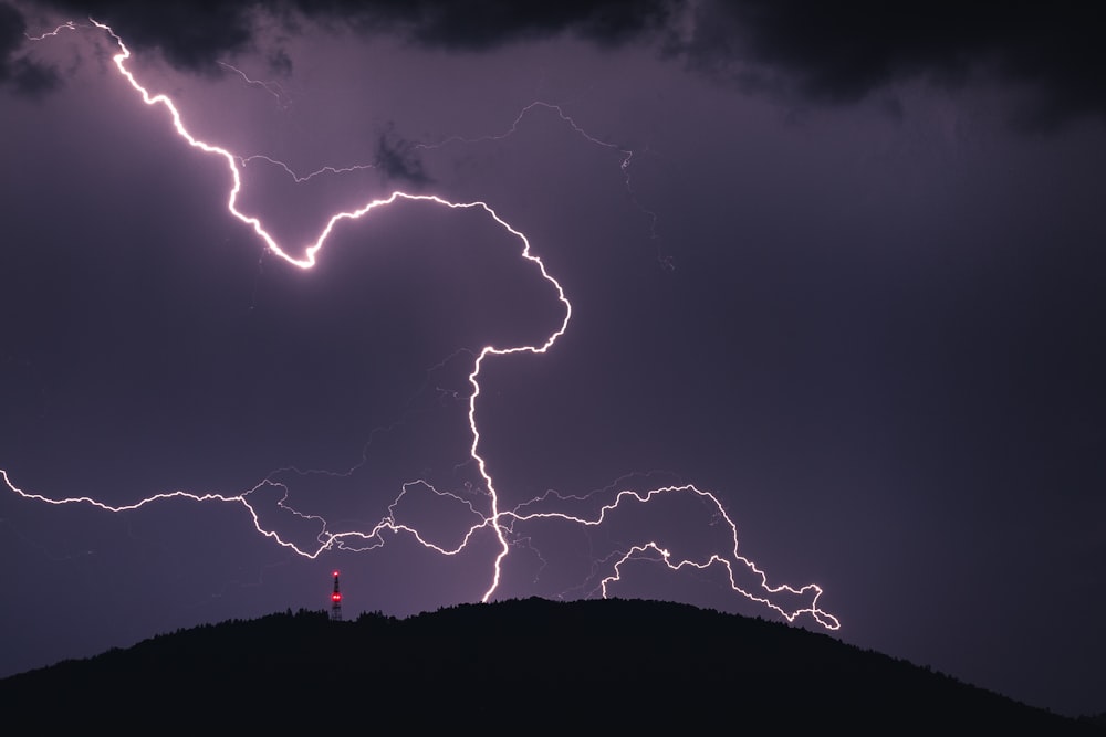 a couple of lightning strikes over a hill