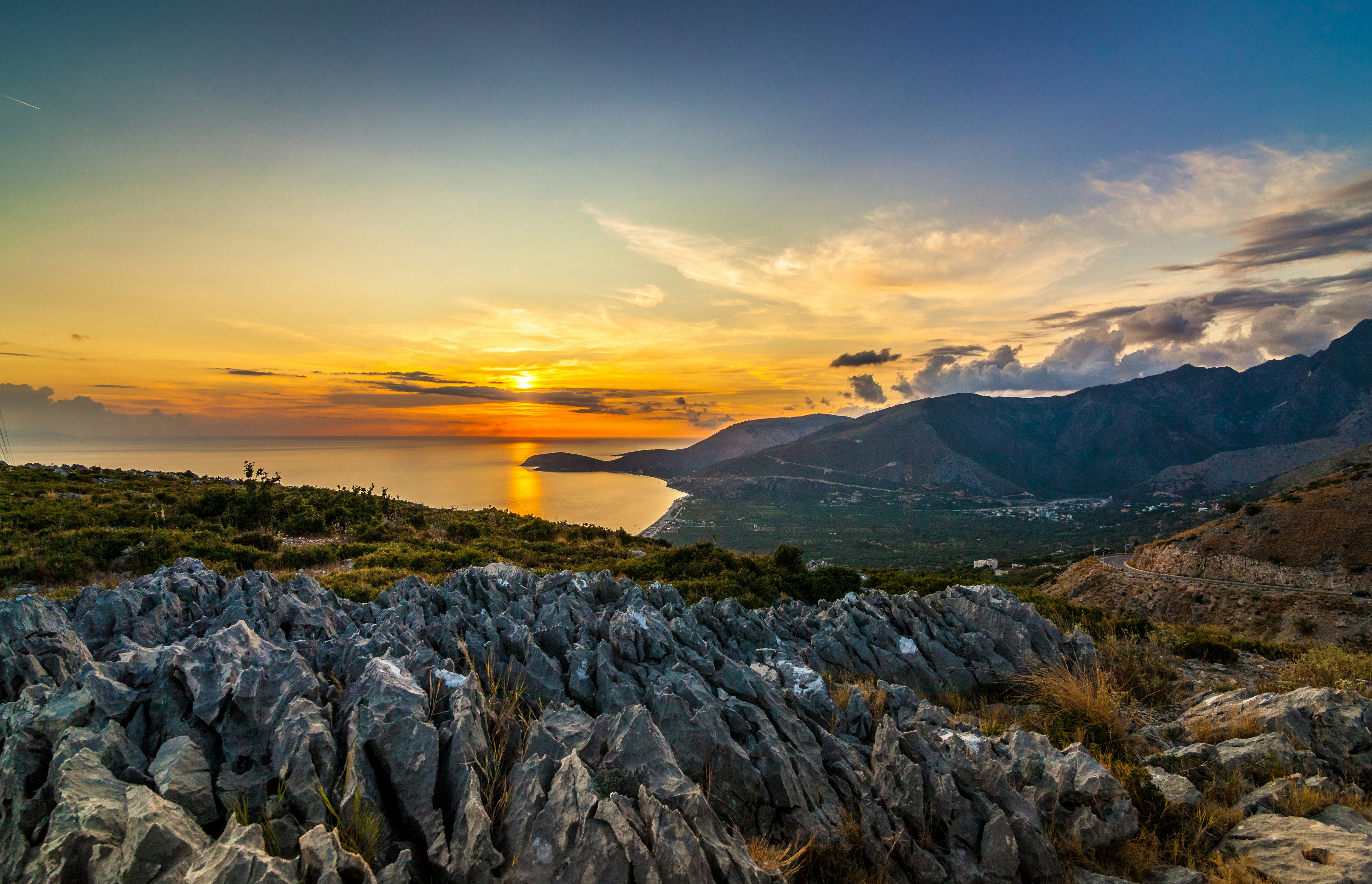 the sun is setting over the ocean and mountains