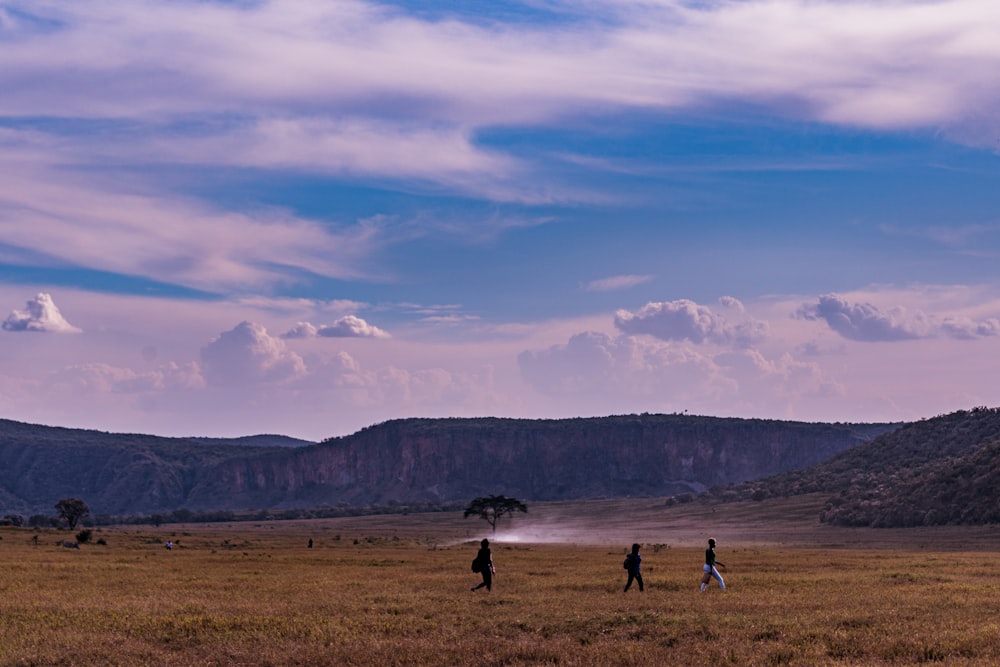 a group of people standing on top of a dry grass field