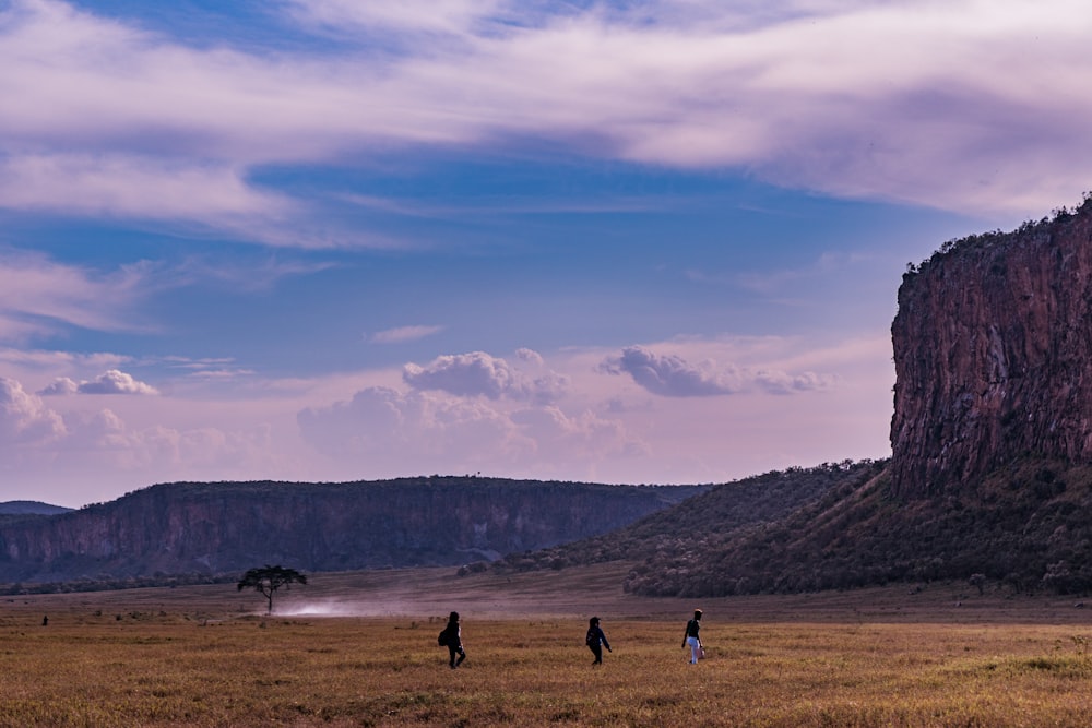 a group of people standing on top of a dry grass field