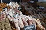 A lively tasting event with producers and visitors sharing saucisson samples.